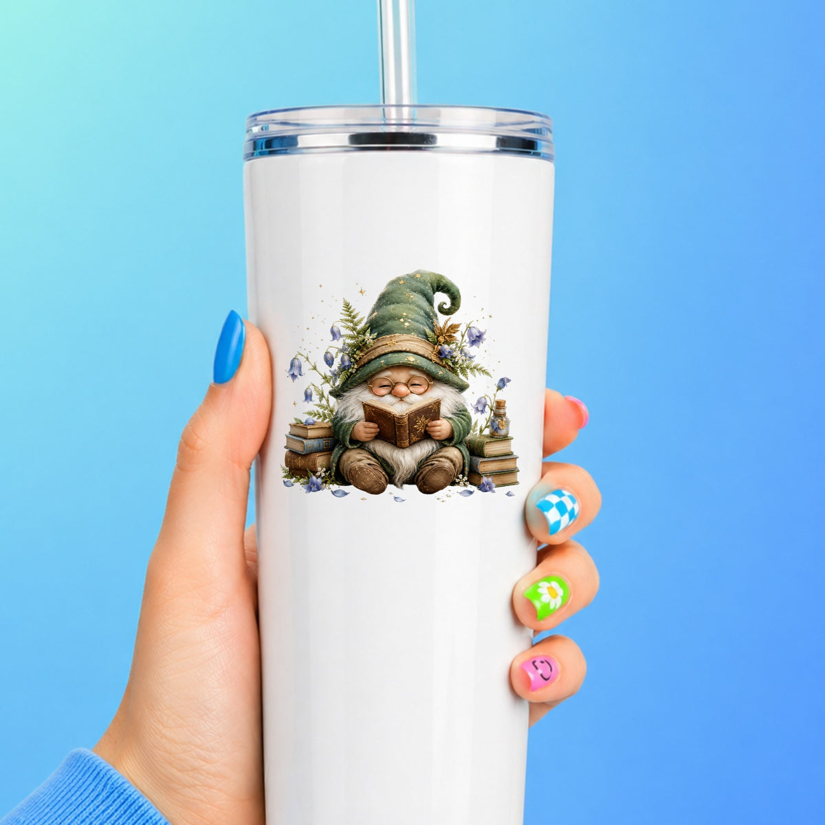 Gnome Reading With Book Stack UV DTF sticker applied to a white straw tumbler on a blue background