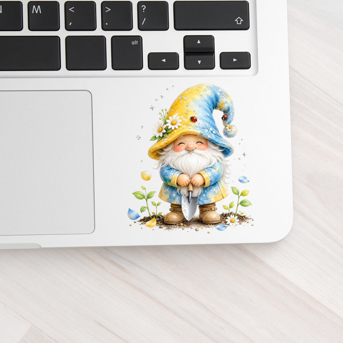 Gardening Gnome With Trowel UV DTF sticker applied to a silver laptop beside the keyboard