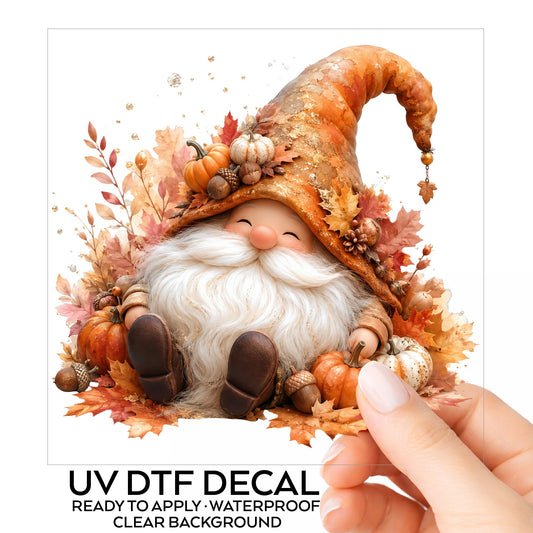 Autumn Gnome With Pumpkins UV DTF sticker on its backing card, held in hand