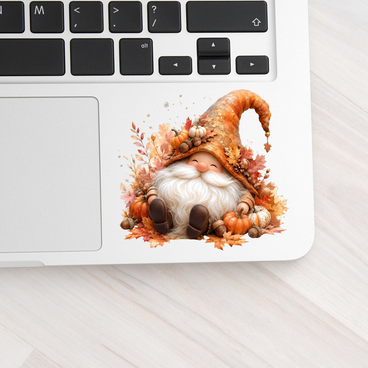 Autumn Gnome With Pumpkins UV DTF sticker applied to a silver laptop beside the keyboard