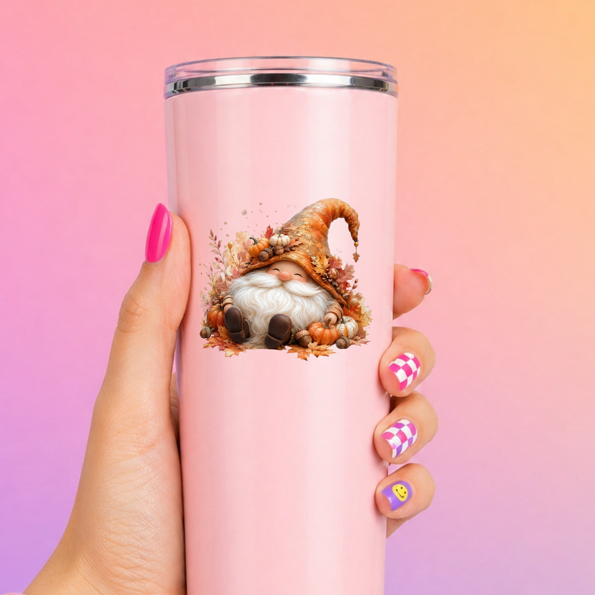 Autumn Gnome With Pumpkins UV DTF sticker applied to a tall pink tumbler on a pink and orange background