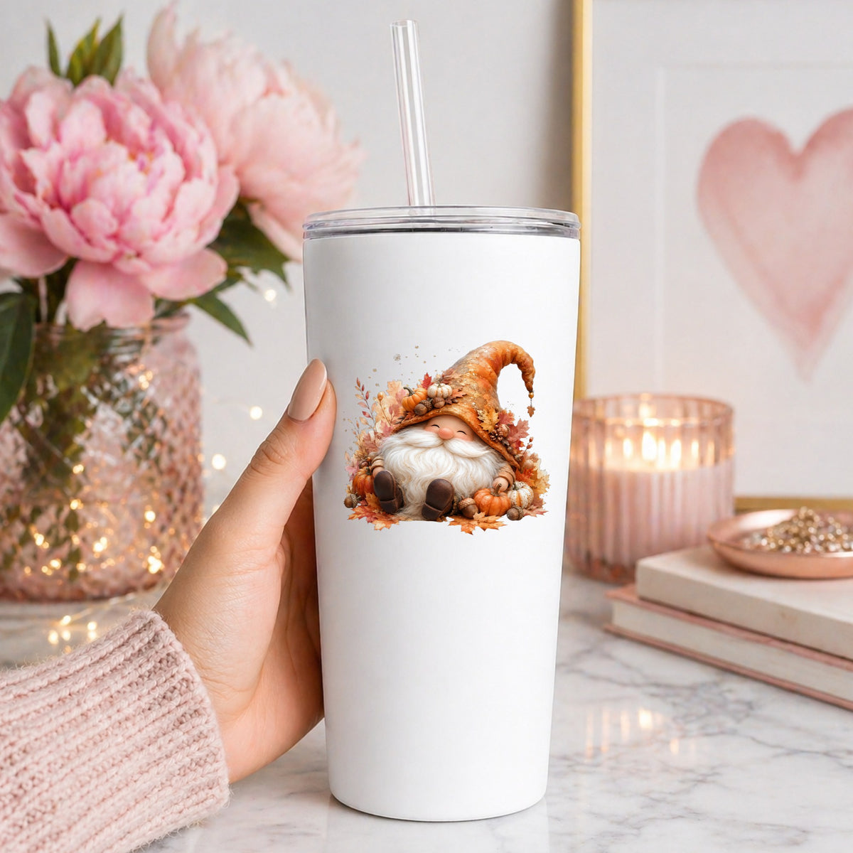 Autumn Gnome With Pumpkins UV DTF sticker applied to a white straw tumbler beside pink peonies