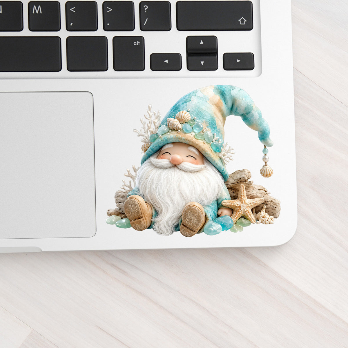 Beach Gnome With Seashells UV DTF sticker applied to a silver laptop beside the keyboard
