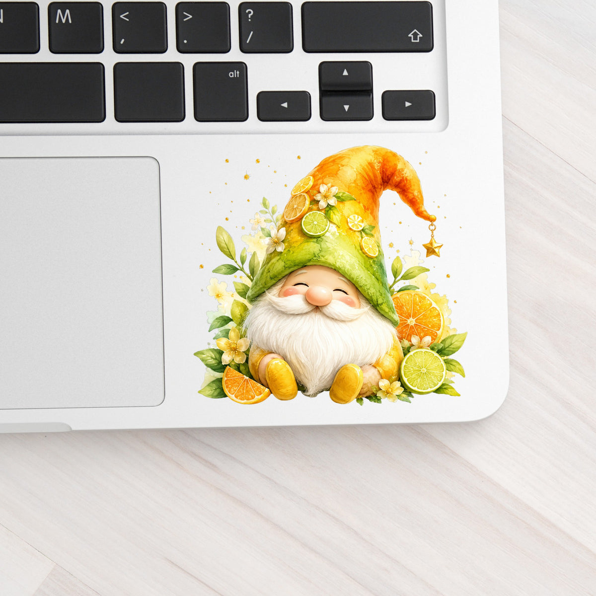 Citrus Gnome With Orange Slices UV DTF sticker applied to a silver laptop beside the keyboard