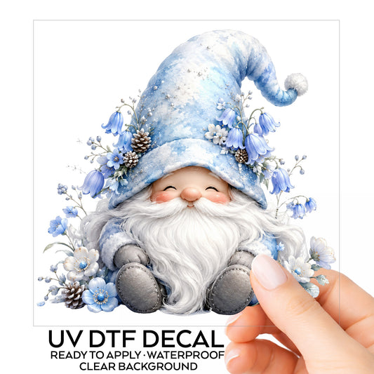 Winter Gnome With Pinecones UV DTF sticker on its backing card, held in hand