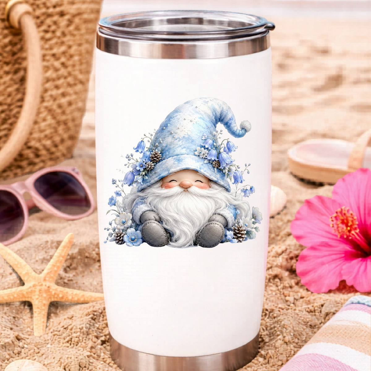 Winter Gnome With Pinecones UV DTF sticker applied to a white travel tumbler on beach sand