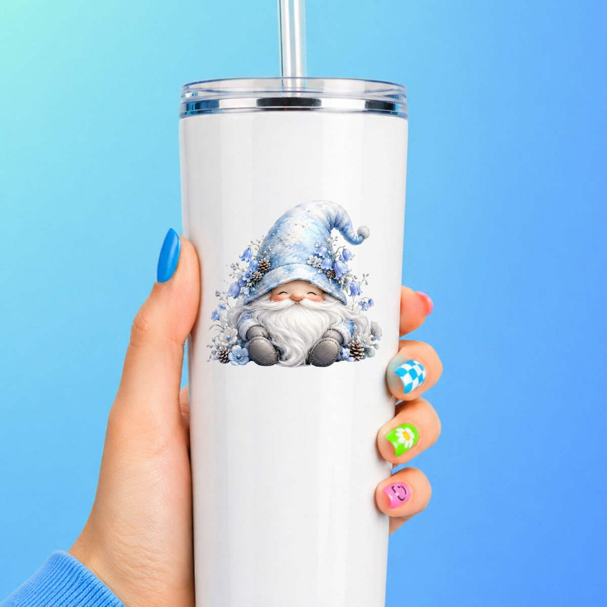 Winter Gnome With Pinecones UV DTF sticker applied to a white straw tumbler on a blue background