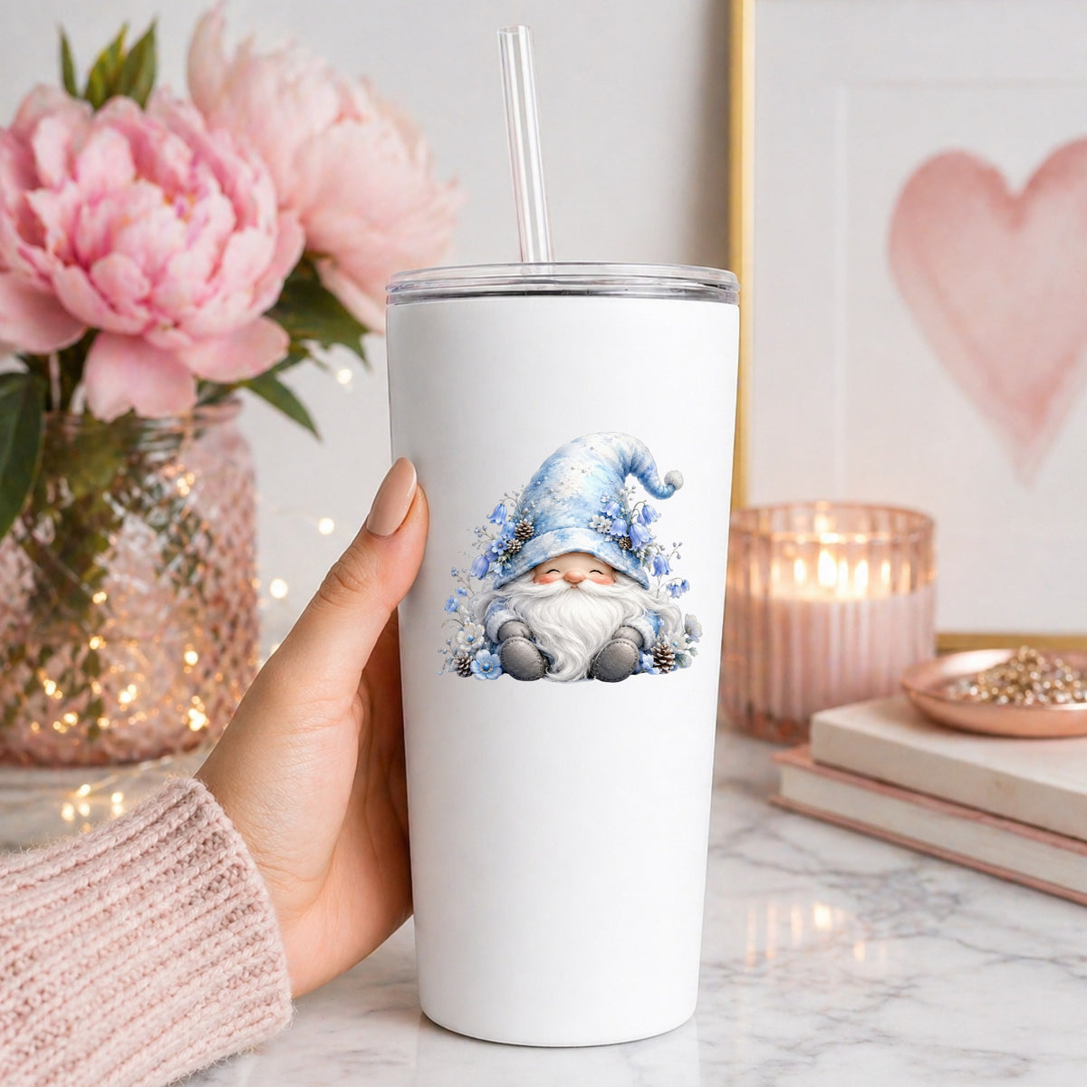 Winter Gnome With Pinecones UV DTF sticker applied to a white straw tumbler beside pink peonies