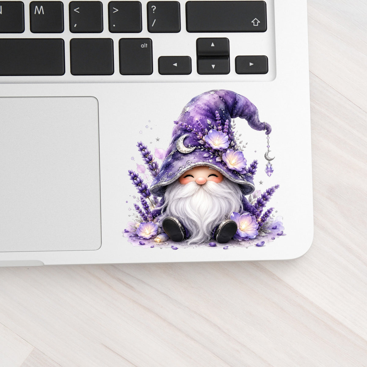Lavender Gnome With Moon Charm UV DTF sticker applied to a silver laptop beside the keyboard