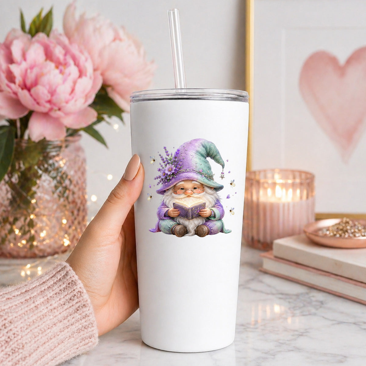 Lavender Reading Gnome With Fireflies UV DTF sticker applied to a white straw tumbler beside pink peonies