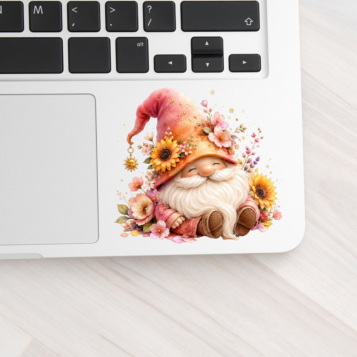 Sunflower Gnome With Pink Flowers UV DTF sticker applied to a silver laptop beside the keyboard