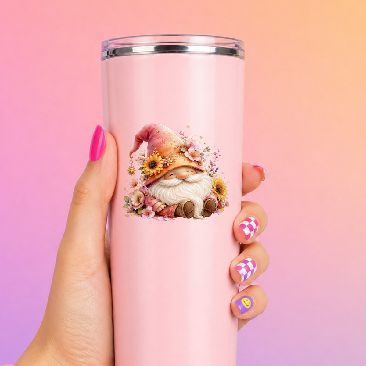 Sunflower Gnome With Pink Flowers UV DTF sticker applied to a tall pink tumbler on a pink and orange background