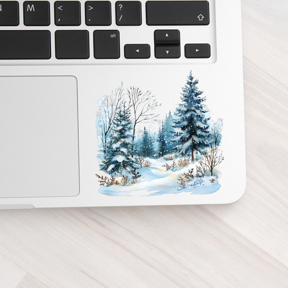 Snowy Pine Forest UV DTF sticker applied to a laptop beside the keyboard