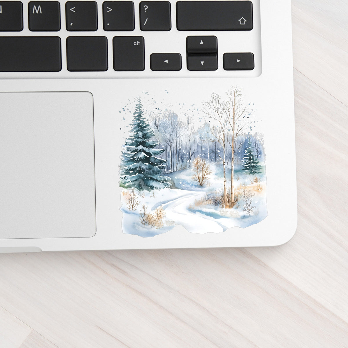 Snowy Forest Path UV DTF sticker applied to a laptop beside the keyboard