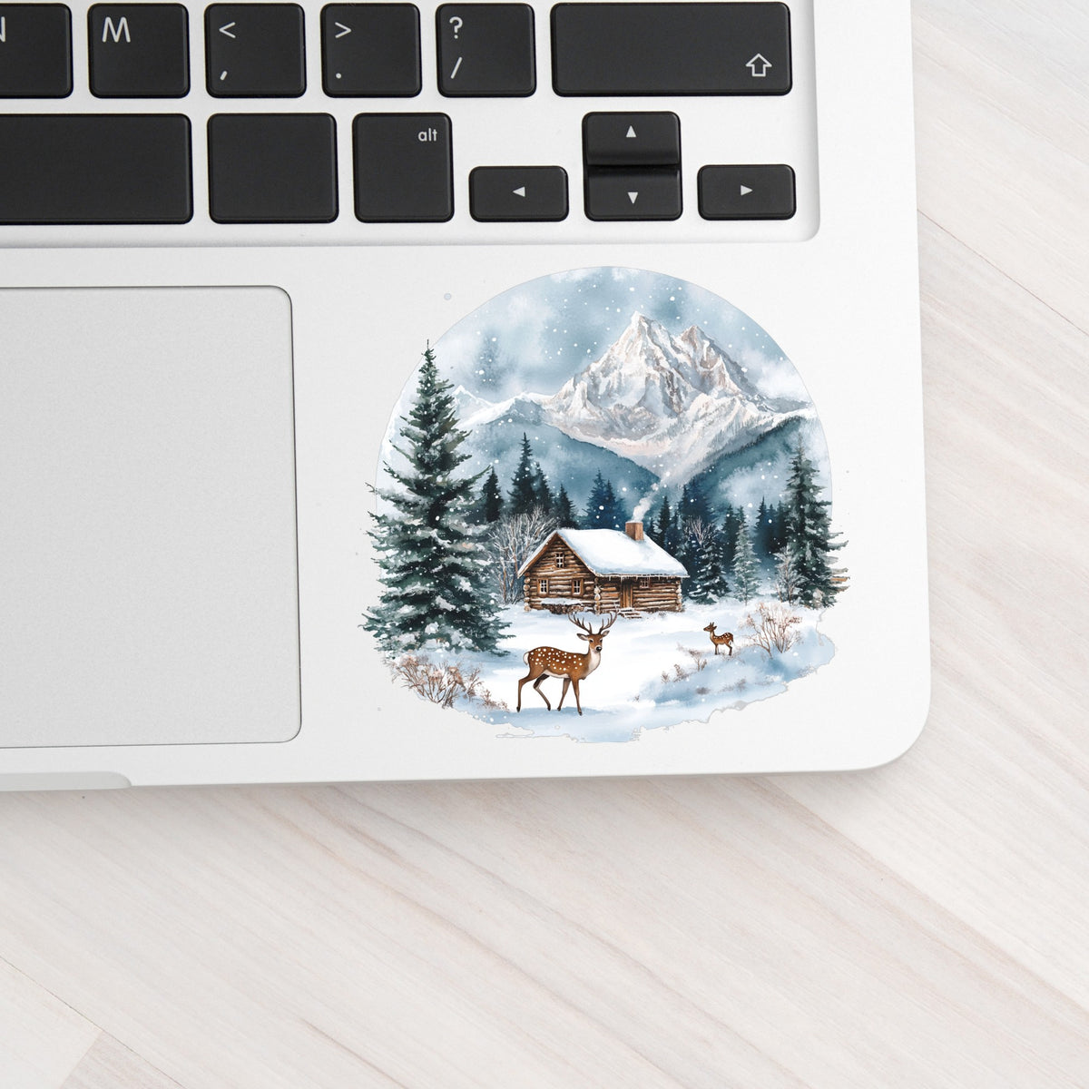 Log Cabin And Deer UV DTF sticker applied to a laptop beside the keyboard