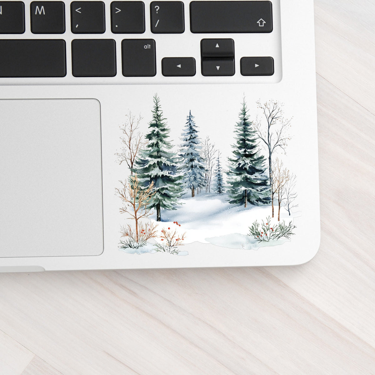 Winter Evergreens With Red Berries UV DTF sticker applied to a laptop beside the keyboard