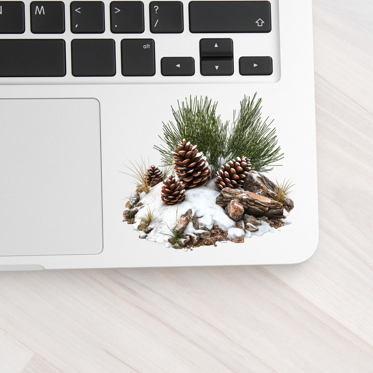 Pine Cones In Snow UV DTF sticker applied to a laptop beside the keyboard