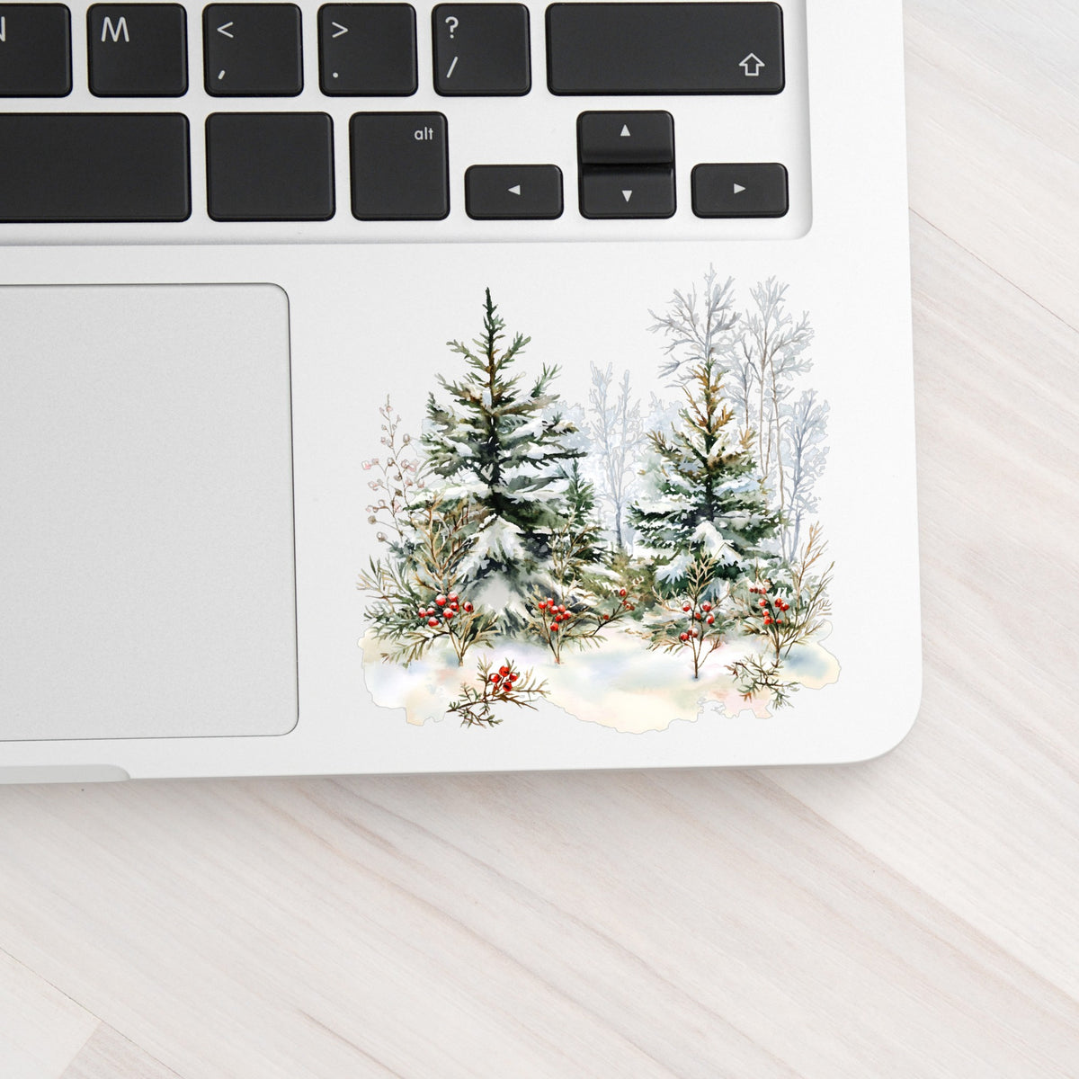 Winter Pine Trees With Berries UV DTF sticker applied to a laptop beside the keyboard