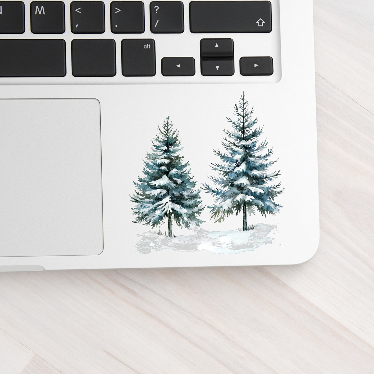 Snowy Evergreen Pair UV DTF sticker applied to a laptop beside the keyboard