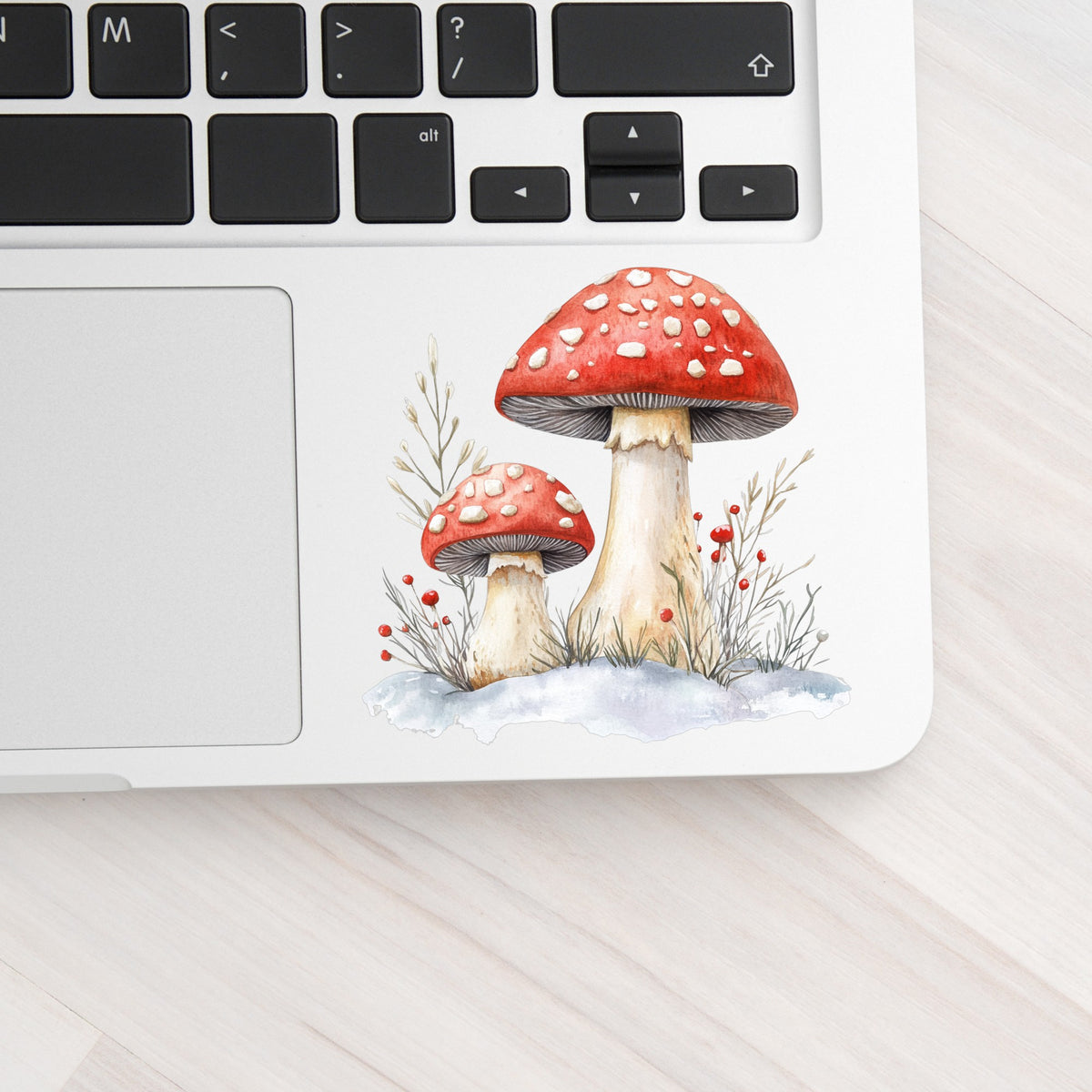 Red Mushrooms In Snow UV DTF sticker applied to a laptop beside the keyboard