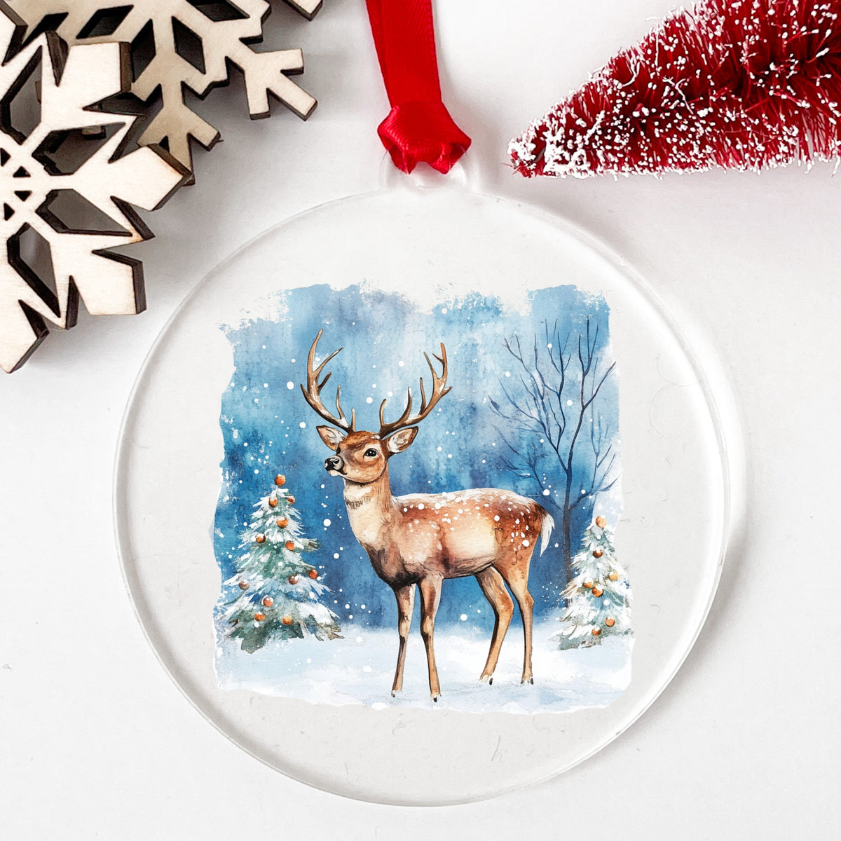 Christmas Deer With Decorated Trees UV DTF sticker applied to a clear acrylic ornament