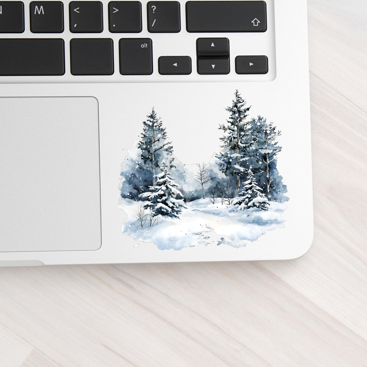 Falling Snow Pine Forest UV DTF sticker applied to a laptop beside the keyboard