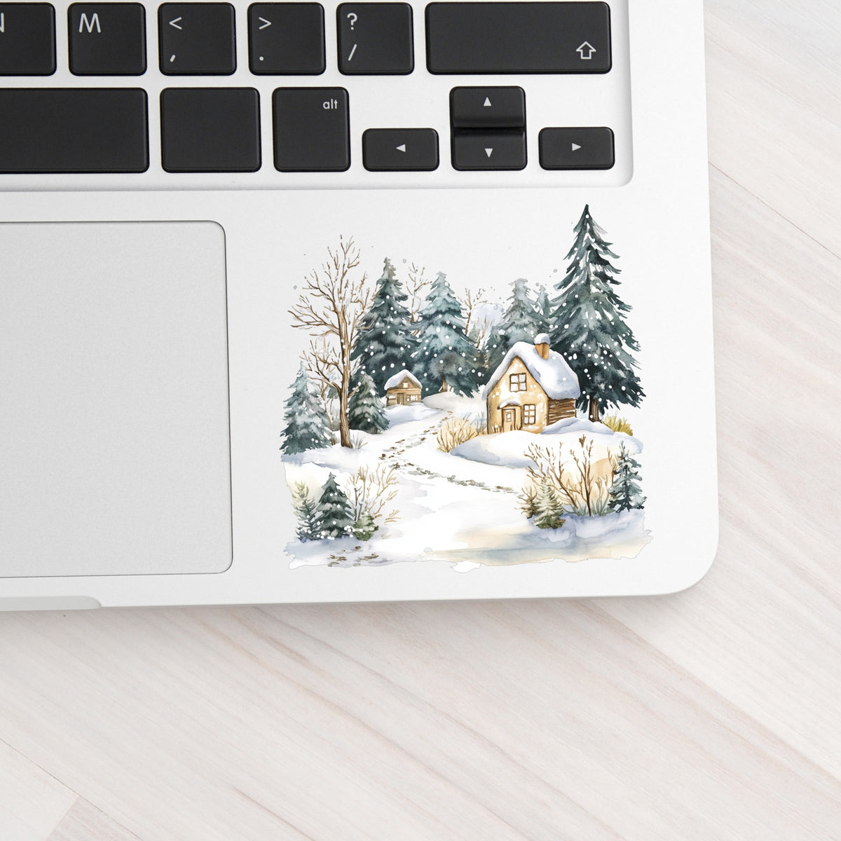 Snowy Cottage Village UV DTF sticker applied to a laptop beside the keyboard