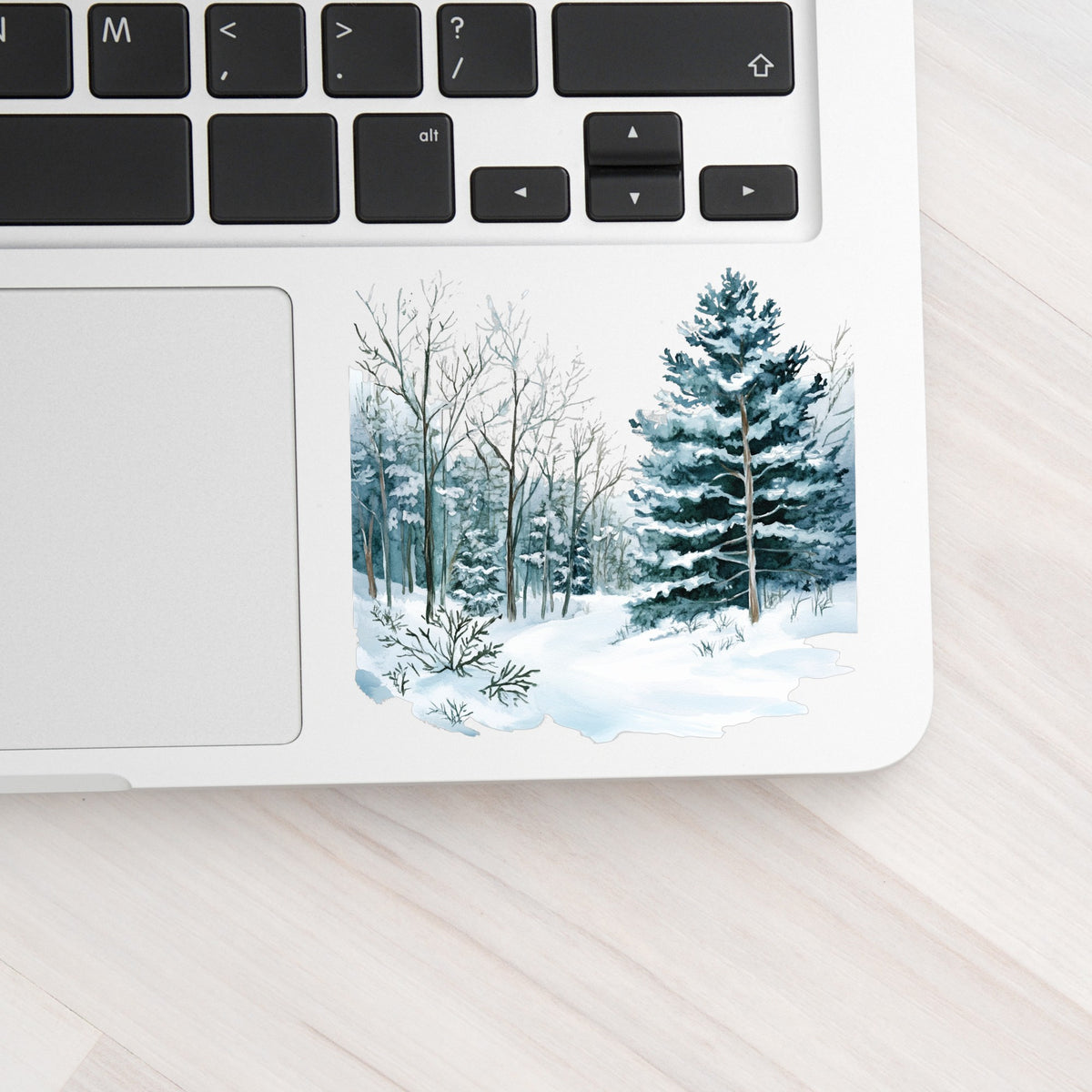 Tall Spruce Winter Forest UV DTF sticker applied to a laptop beside the keyboard