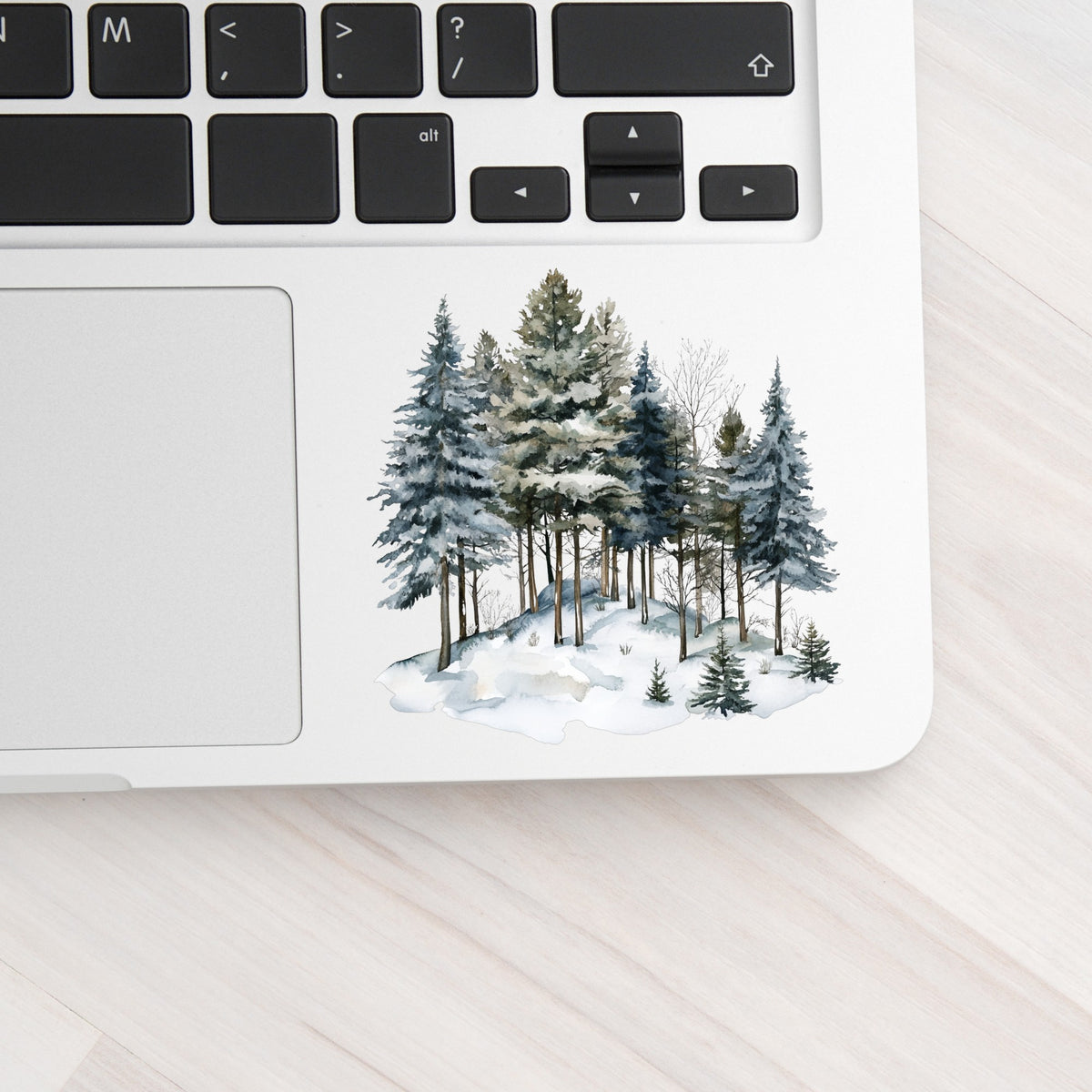 Snowy Pine Hillside UV DTF sticker applied to a laptop beside the keyboard