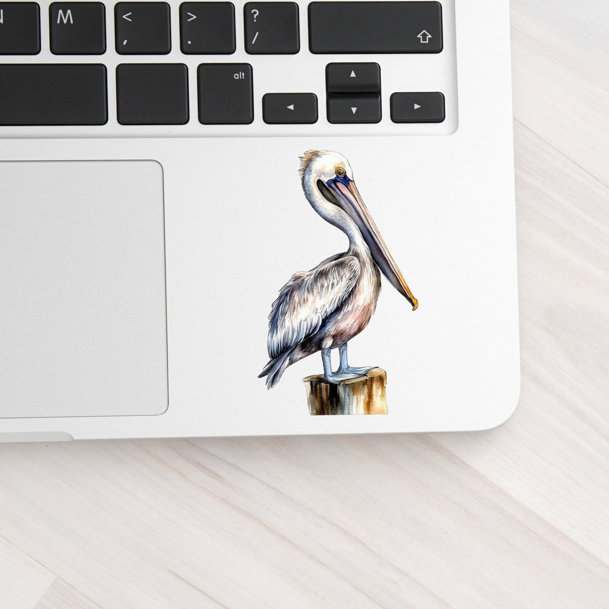 Pelican On Wood Post UV DTF sticker applied to a laptop beside the keyboard