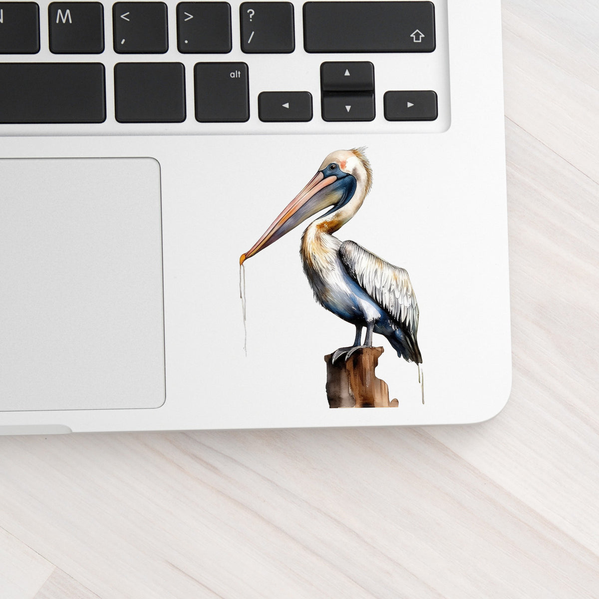 Pelican Perched On Piling UV DTF sticker applied to a laptop beside the keyboard