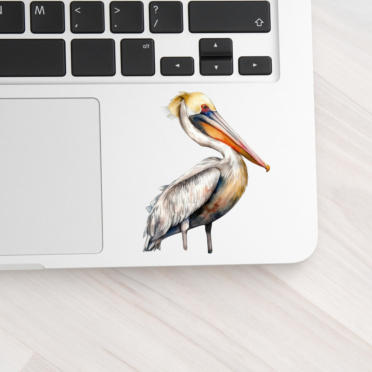 Yellow Crest Pelican UV DTF sticker applied to a laptop beside the keyboard