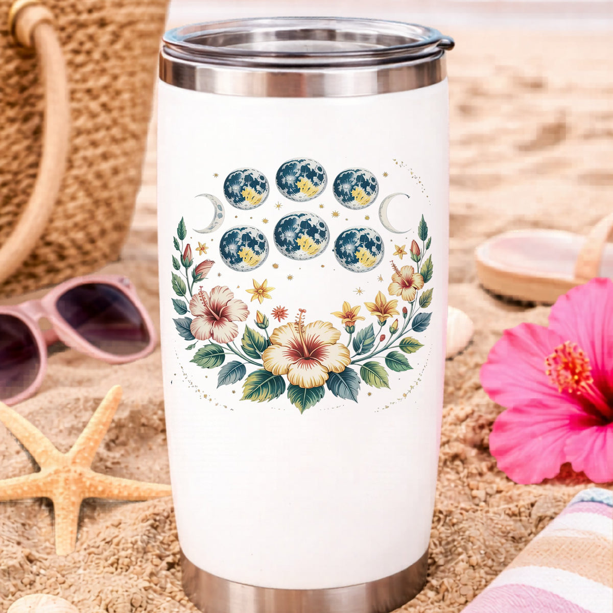 Moon Phases With Hibiscus Flowers UV DTF sticker applied to a white travel tumbler on beach sand
