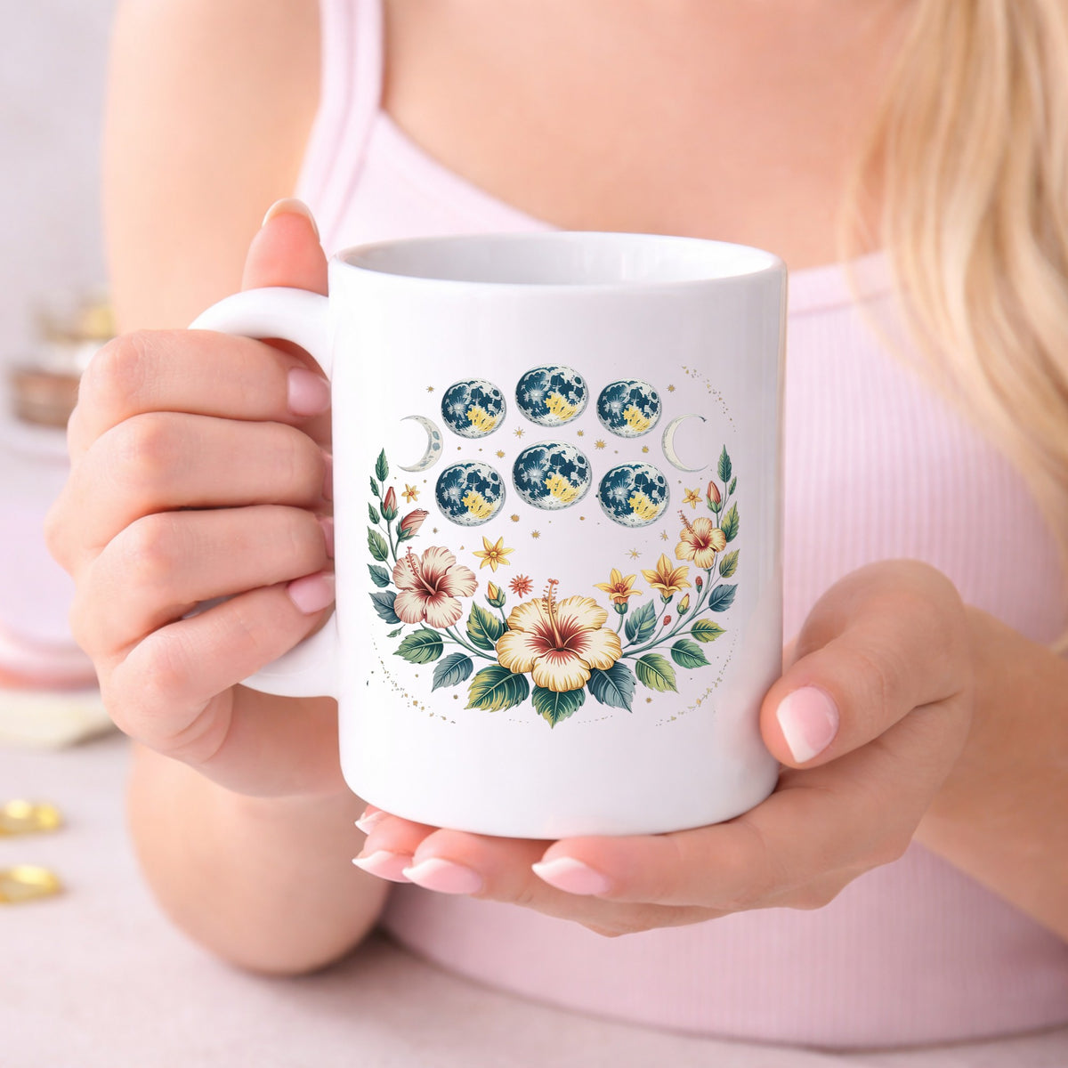 Moon Phases With Hibiscus Flowers UV DTF sticker applied to a white coffee mug held in both hands