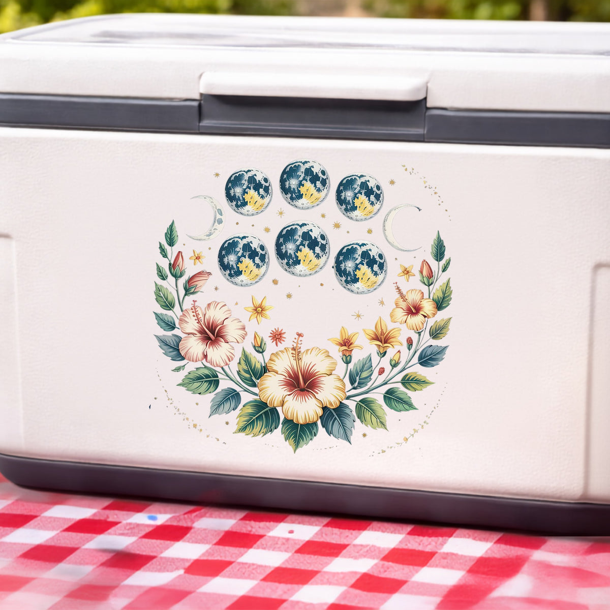 Moon Phases With Hibiscus Flowers UV DTF sticker applied to a white cooler on a red gingham cloth