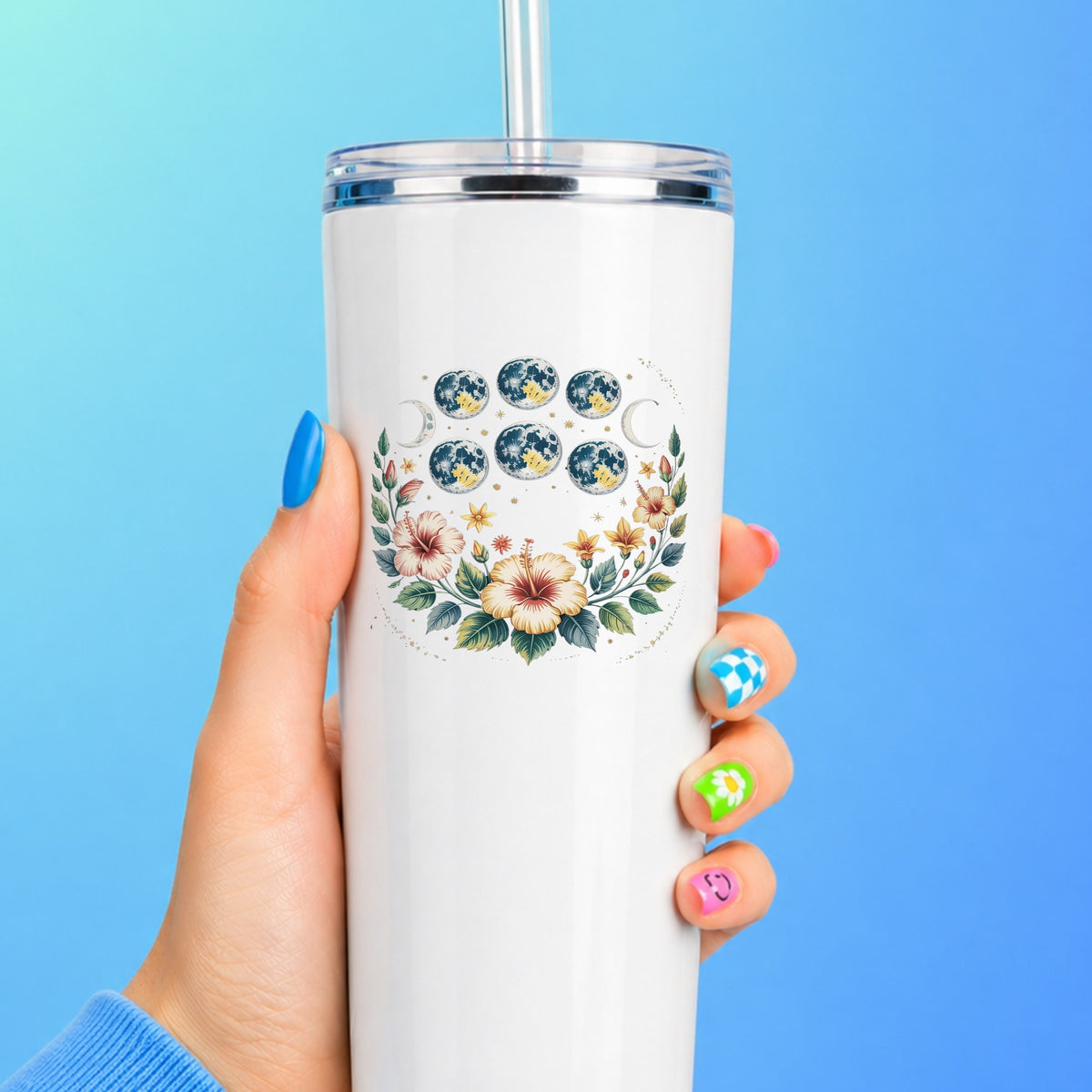 Moon Phases With Hibiscus Flowers UV DTF sticker applied to a white straw tumbler on a blue background
