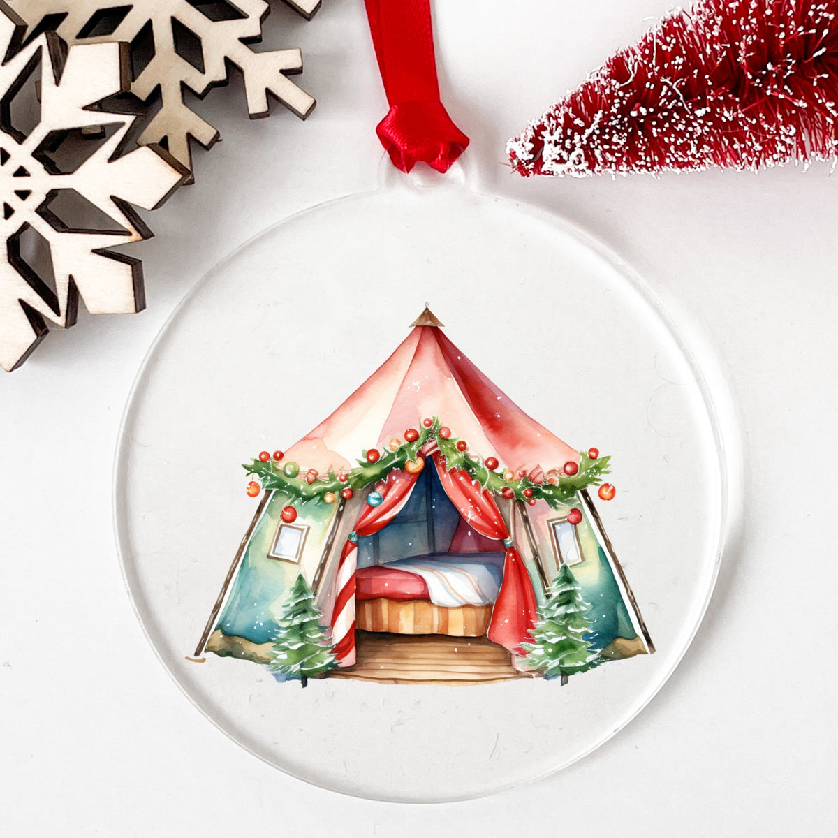 Christmas Glamping Tent UV DTF sticker applied to a clear round acrylic ornament with a red ribbon