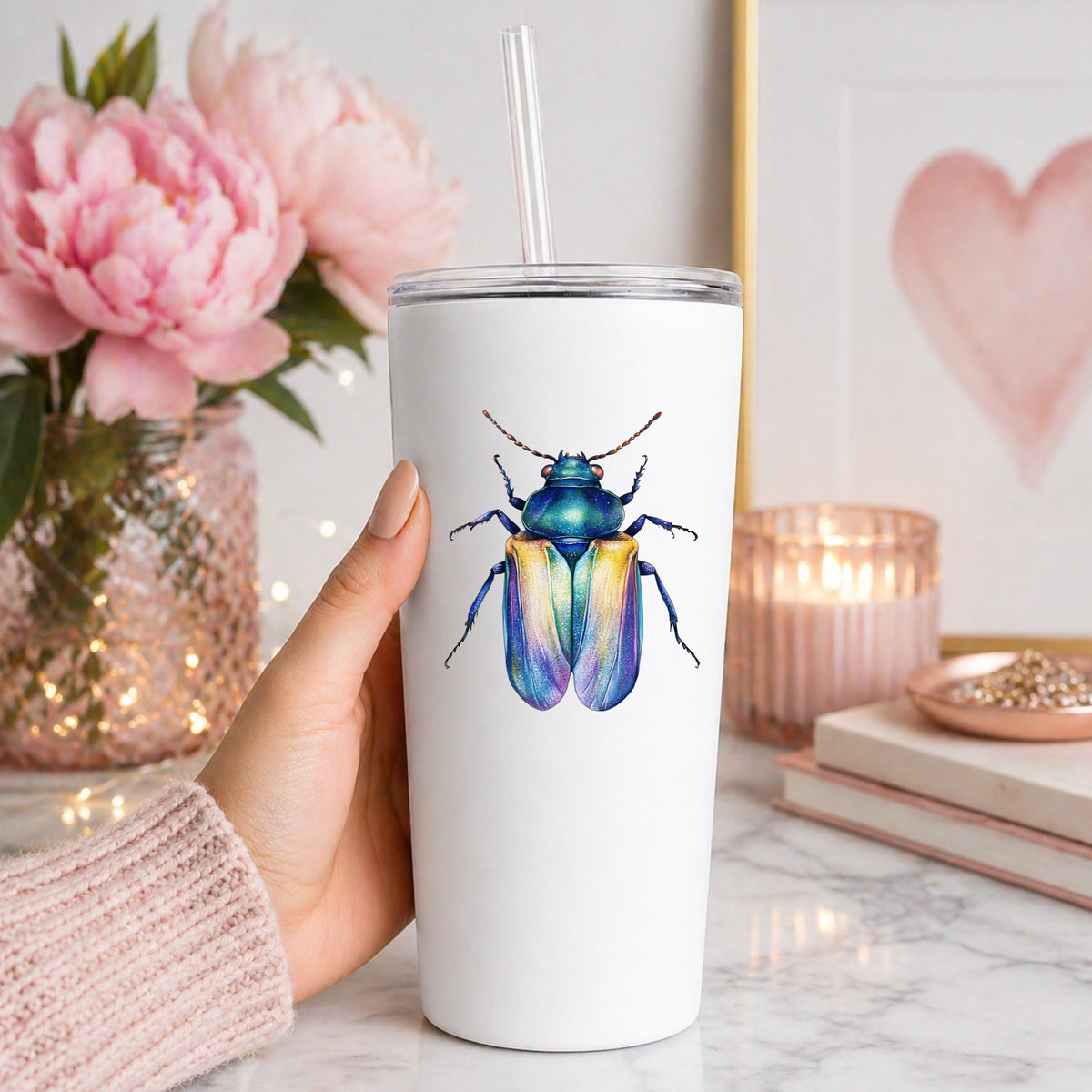 Gold And Blue Jewel Beetle UV DTF sticker applied to a white straw tumbler beside pink peonies