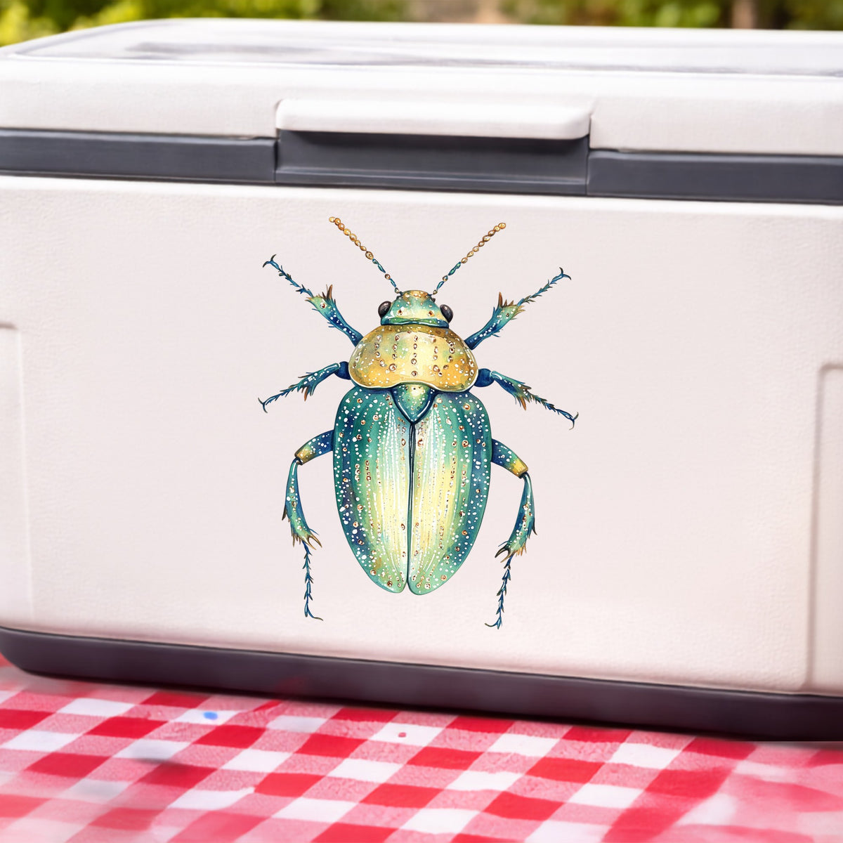 White Dotted Teal Beetle UV DTF sticker applied to a white cooler on a red gingham cloth