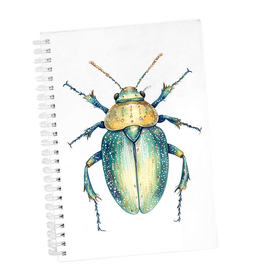 White Dotted Teal Beetle UV DTF sticker applied to the cover of a white spiral journal