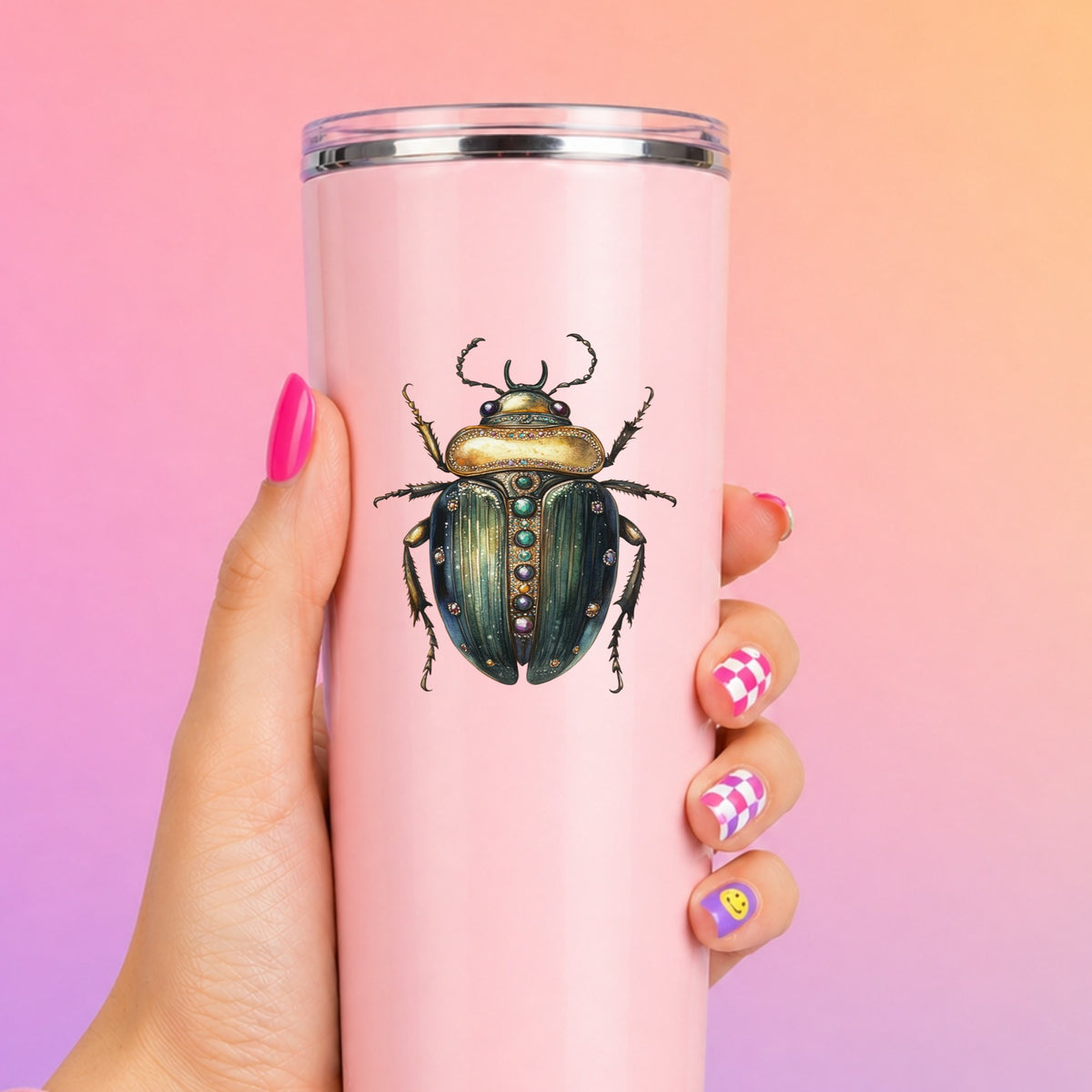 Jeweled Gold Scarab Beetle UV DTF sticker applied to a tall pink tumbler on a pink and orange background