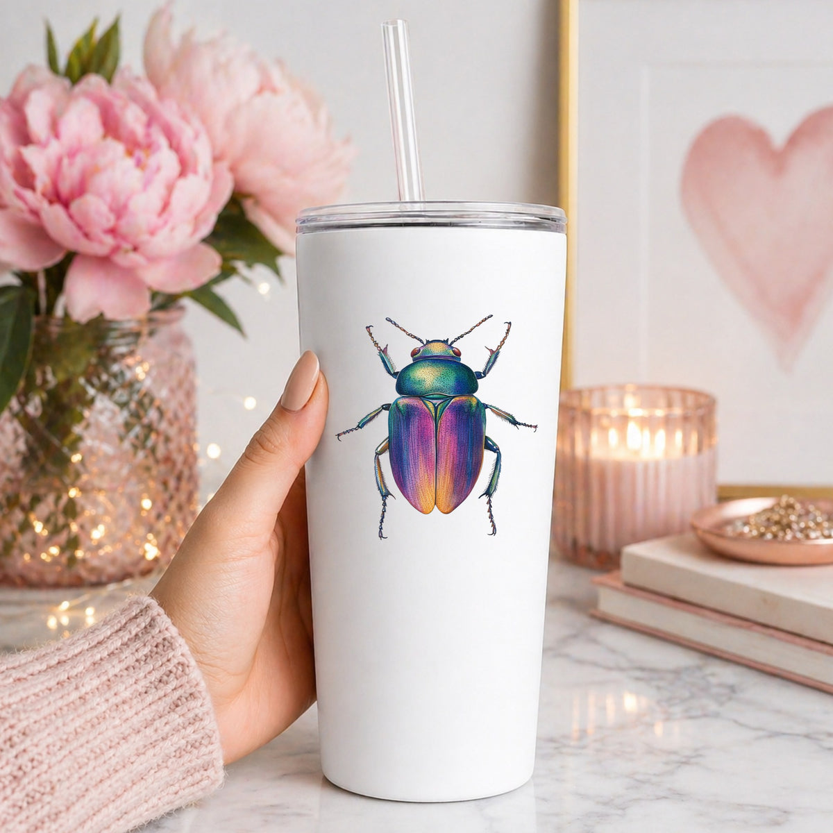 Rainbow Iridescent Beetle UV DTF sticker applied to a white straw tumbler beside pink peonies