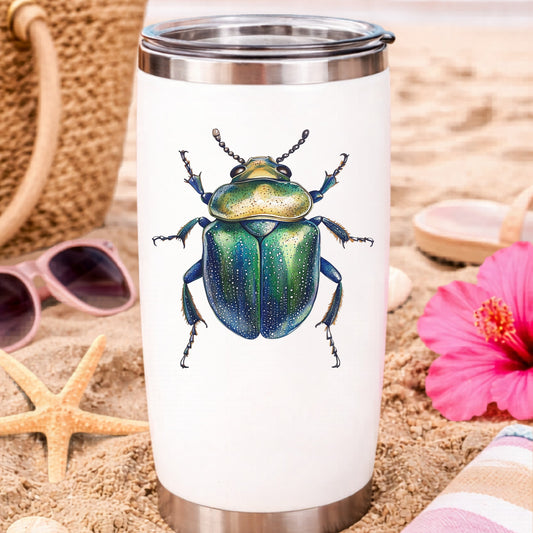 Speckled Green Beetle UV DTF sticker applied to a white travel tumbler on beach sand