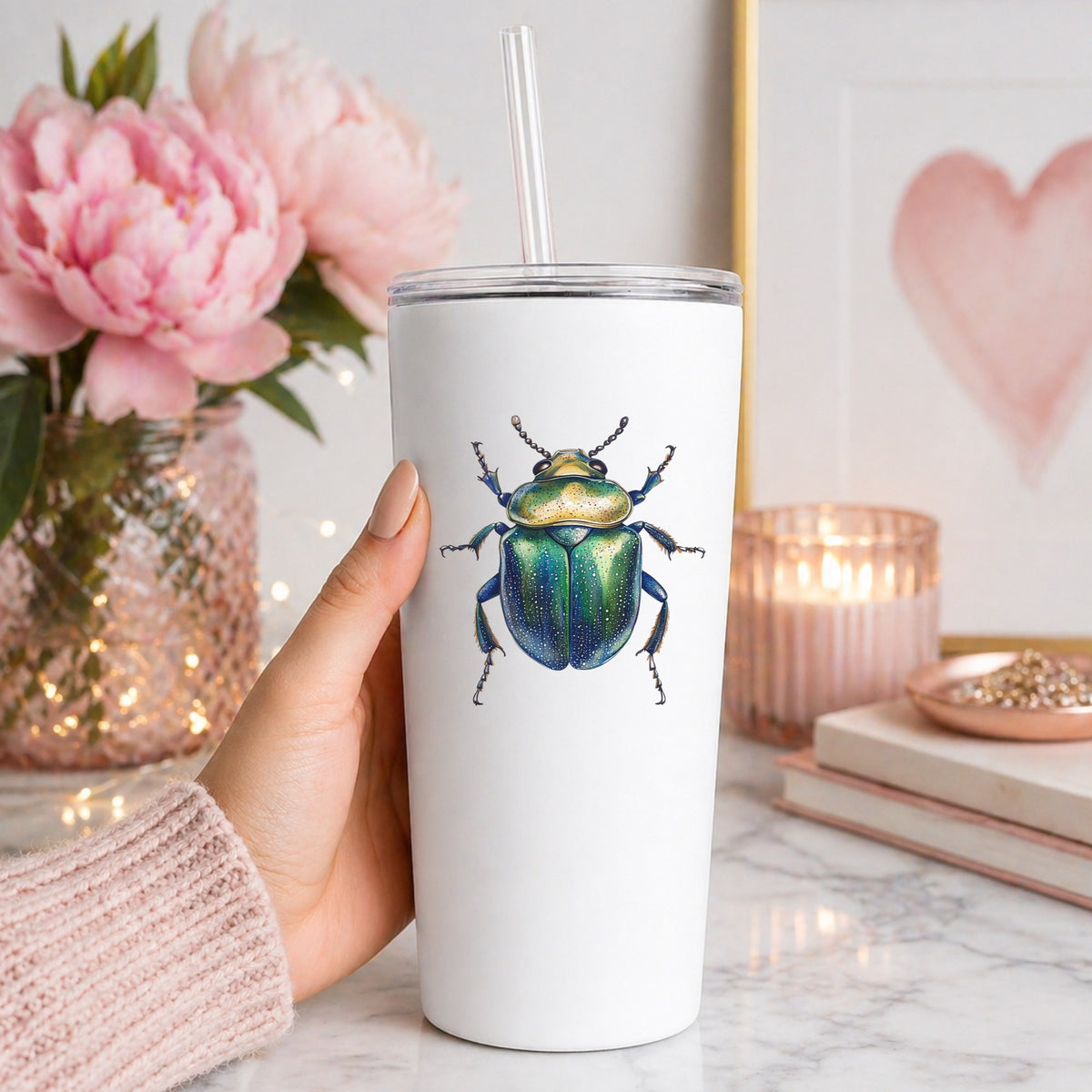 Speckled Green Beetle UV DTF sticker applied to a white straw tumbler beside pink peonies
