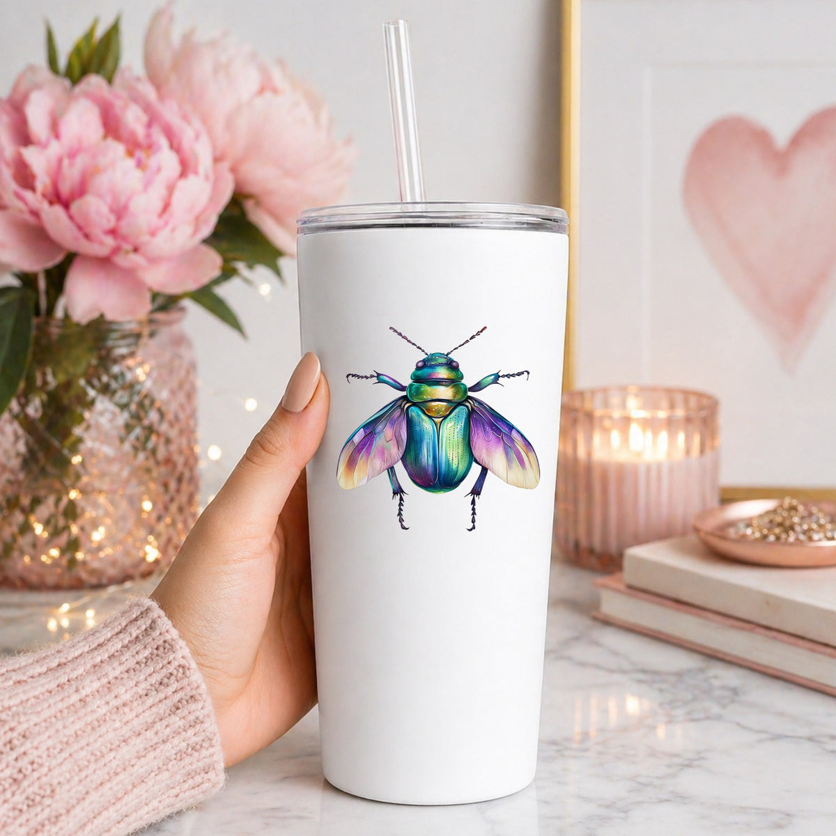 Flying Beetle With Open Wings UV DTF sticker applied to a white straw tumbler beside pink peonies