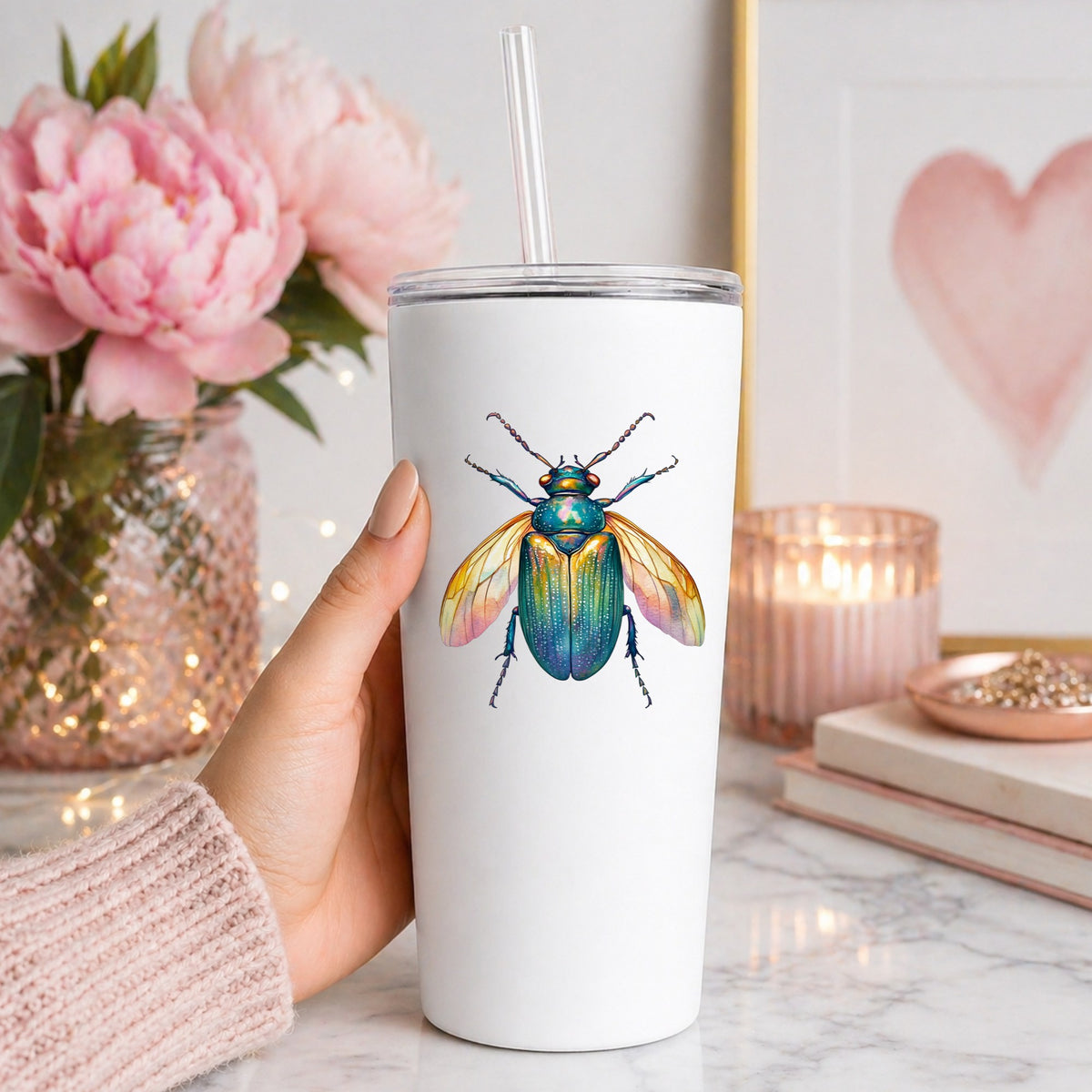 Golden Winged Flying Beetle UV DTF sticker applied to a white straw tumbler beside pink peonies