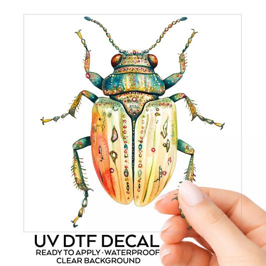Cream And Coral Jeweled Beetle UV DTF sticker on its backing card, held in hand