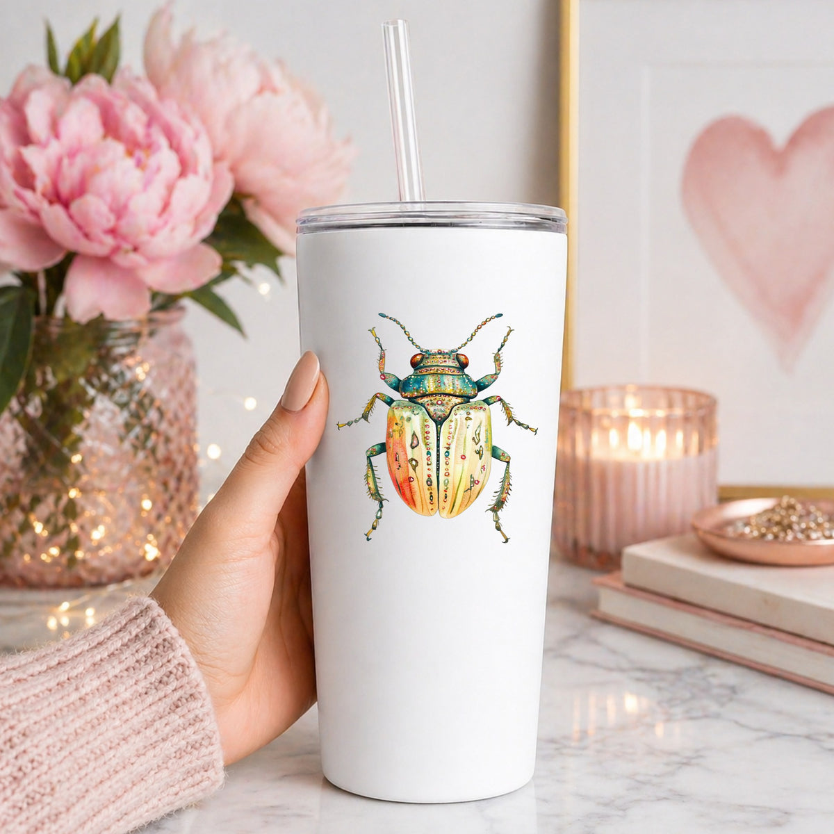 Cream And Coral Jeweled Beetle UV DTF sticker applied to a white straw tumbler beside pink peonies