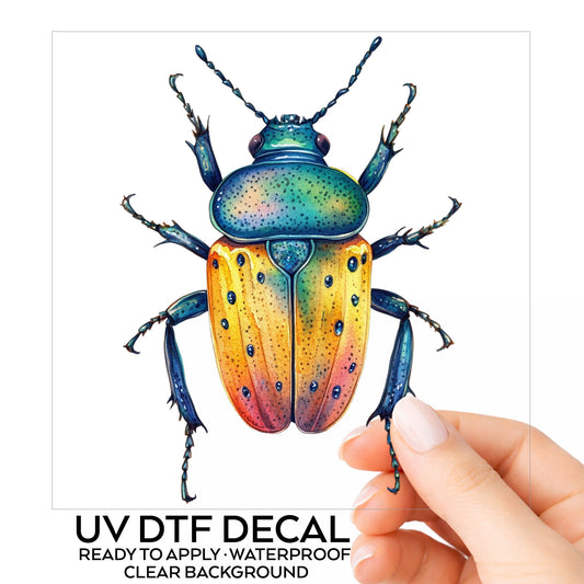 Orange And Blue Spotted Beetle UV DTF sticker on its backing card, held in hand