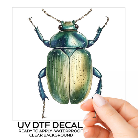 Green Scarab Beetle UV DTF sticker on its backing card, held in hand